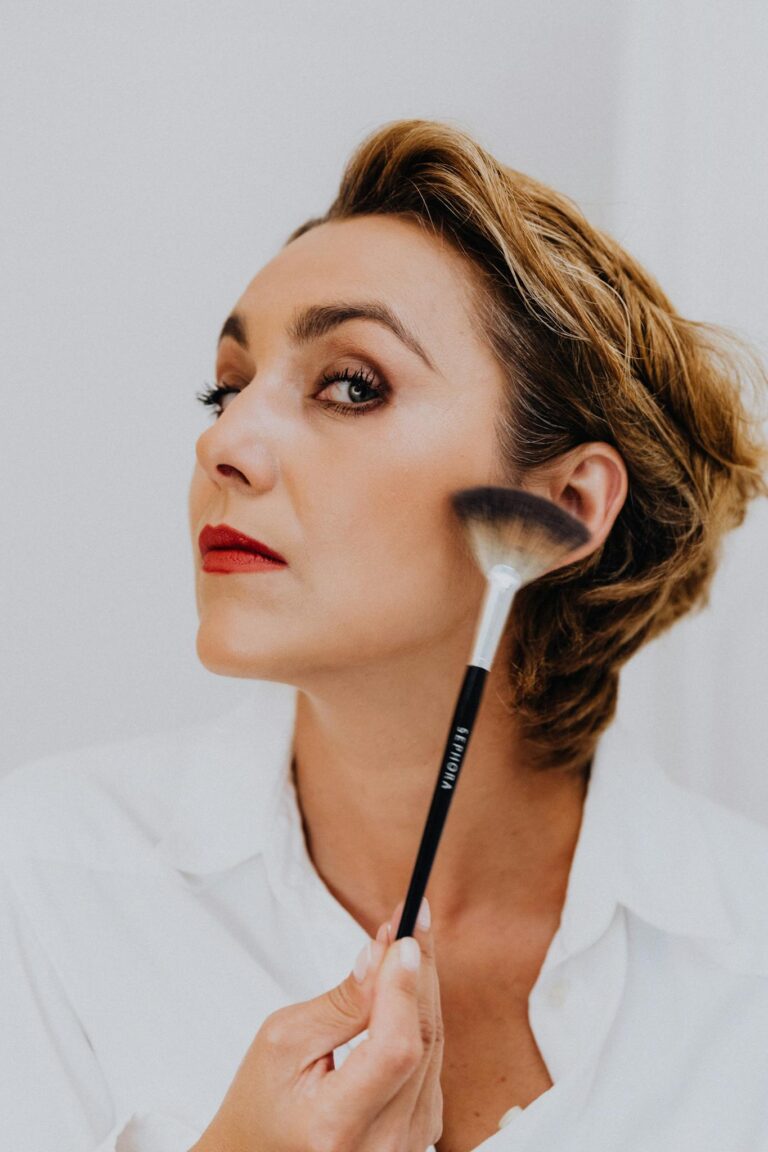 A sophisticated woman applying makeup with a brush, showcasing elegant beauty and cosmetic application.