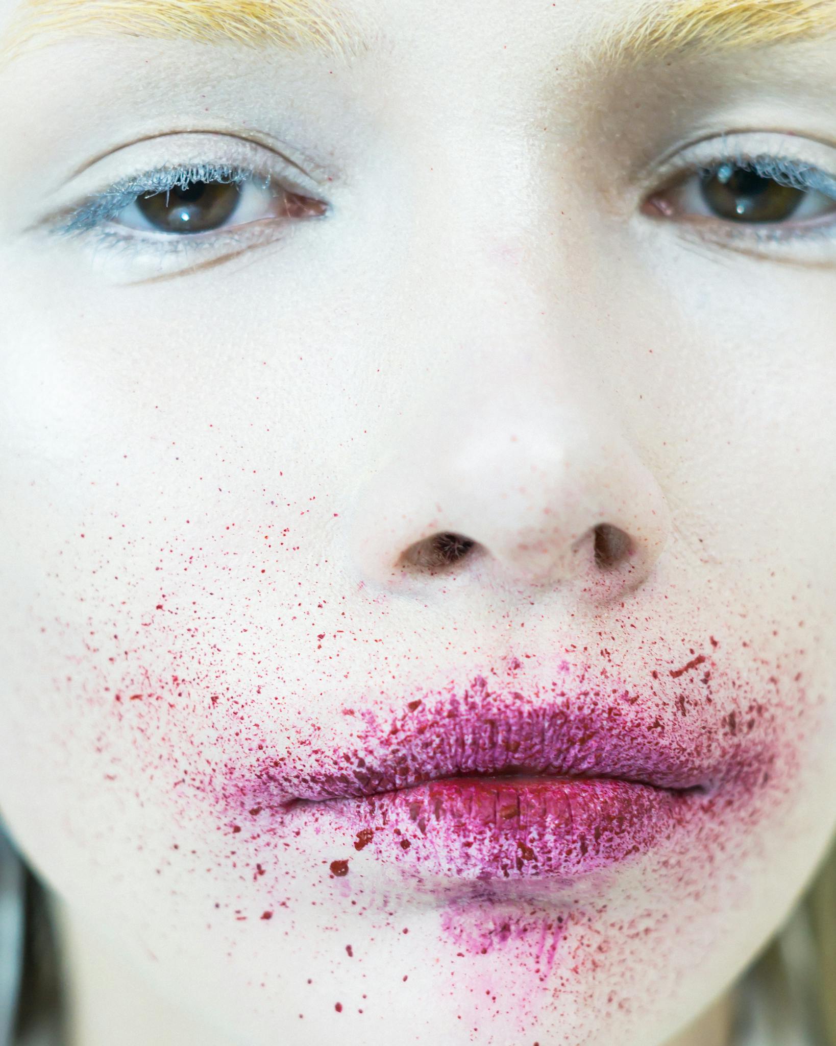 Artistic close-up portrait features splattered pink makeup for a striking visual effect.