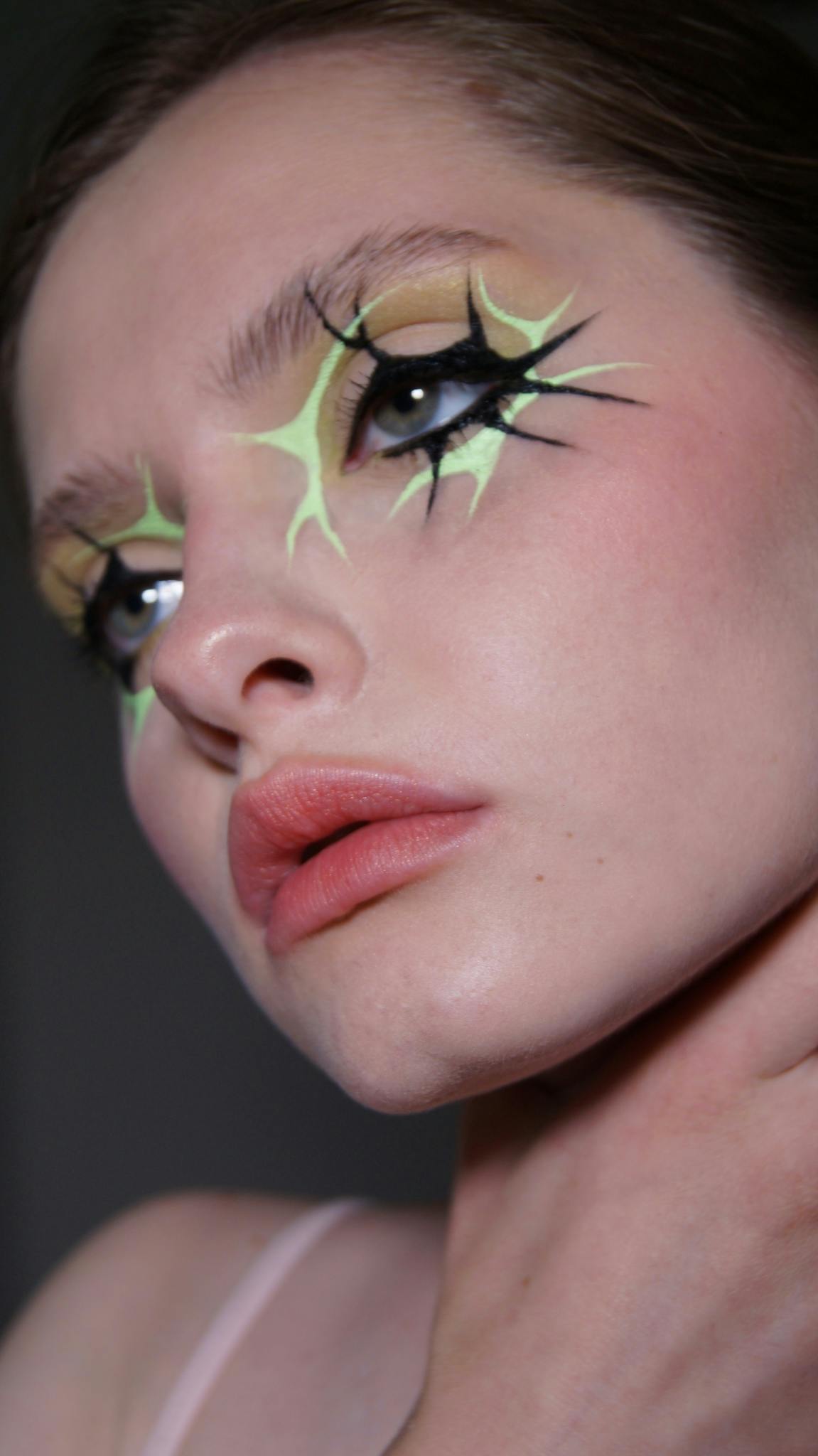 Close-up portrait of a woman with creative artistic makeup in a studio setting.